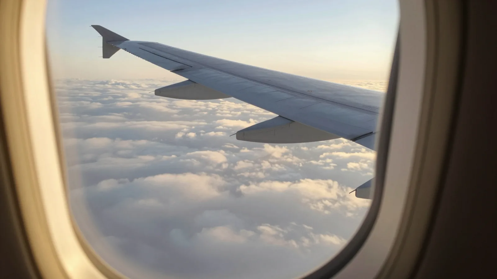 View of an airplane wing above the clouds at sunrise