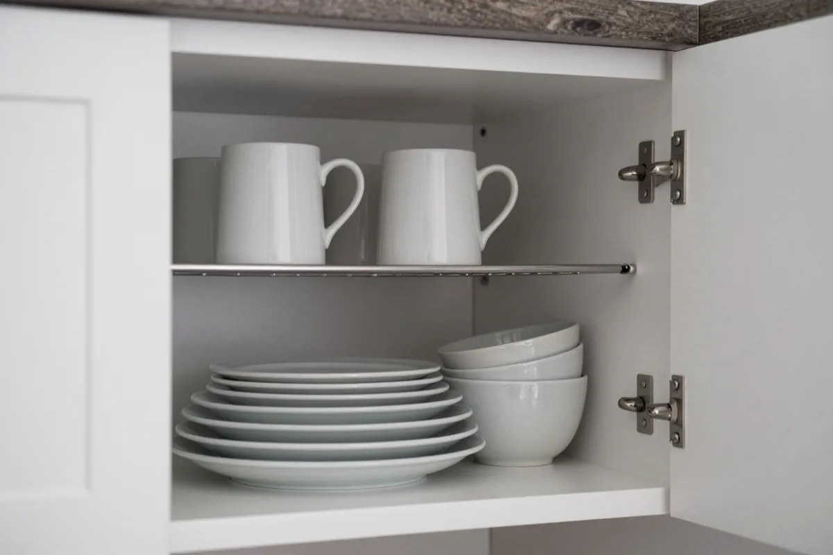 A cabinet shelf riser doubling storage for plates and mugs