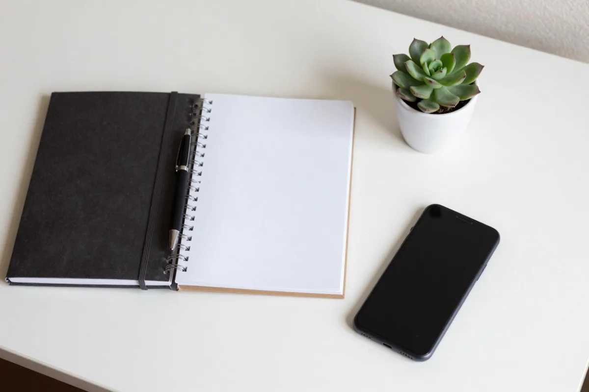 A notebook, pen and phone on a desk for planning a loan
