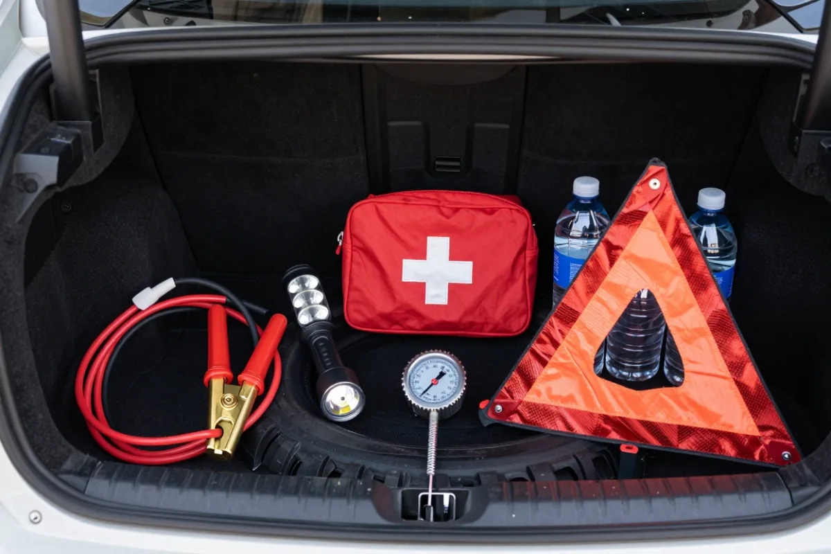 A car emergency kit with jumper cables and a flashlight