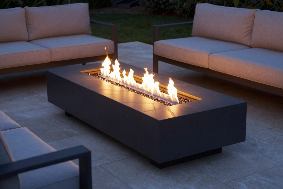 A gas fire table burning on a stone patio in the evening