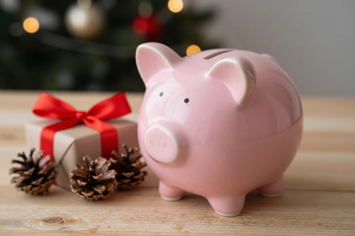 A piggy bank beside a wrapped gift, saving for the holidays